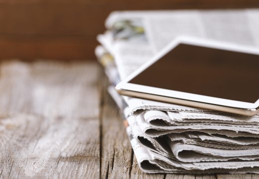 Newspaper and digital tablet on wooden table